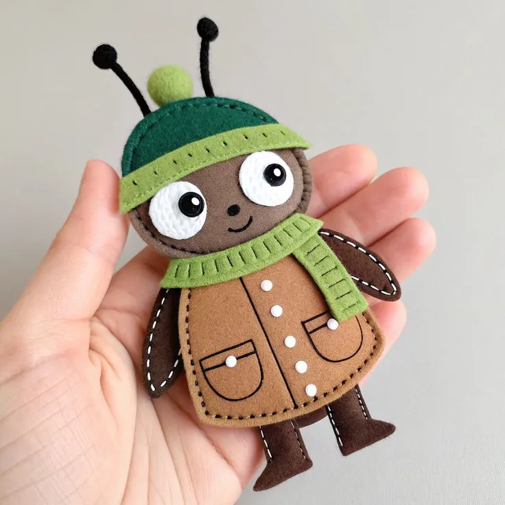 Finished felt ant in a brown coat, green pompom hat and scarf, sewn from KoraLoveDesigns Volume 6