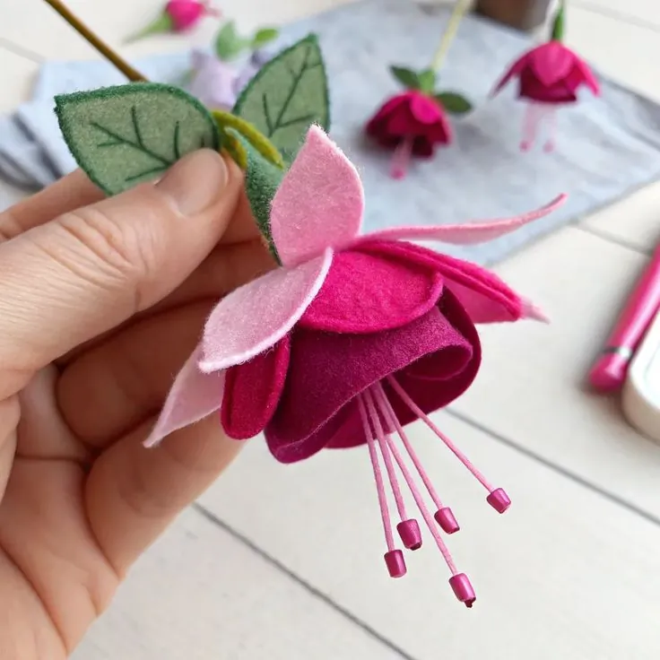 Finished layered felt fuchsia flower in pink and burgundy with beaded stamens and green leaves