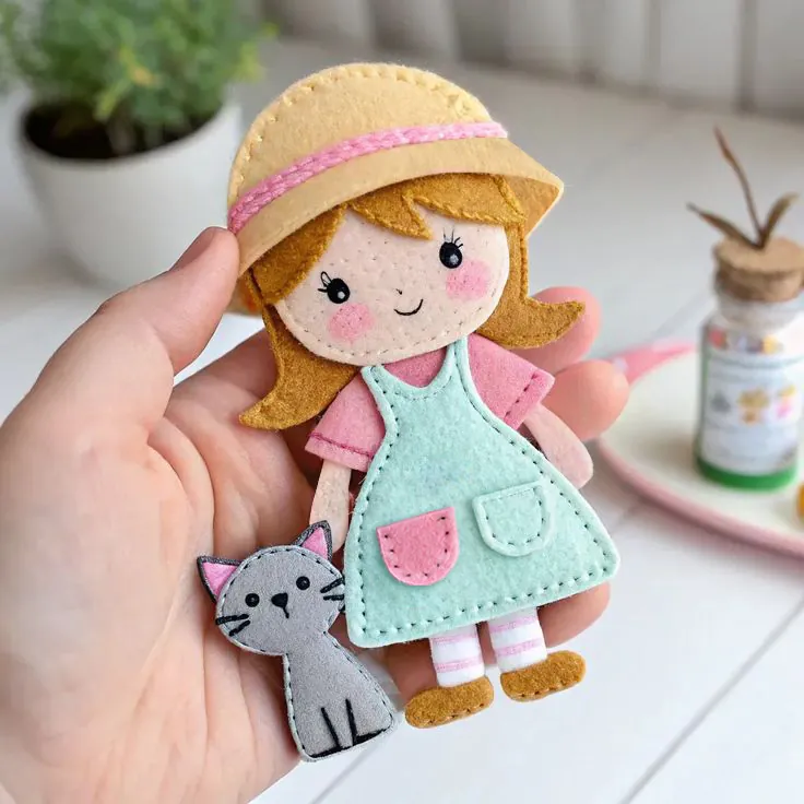 Finished small felt gardener doll in a straw sun hat and mint apron with a grey kitten
