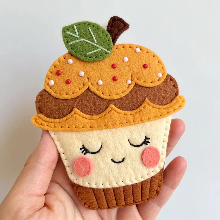 Finished smiling felt pumpkin cupcake with beaded sprinkles and a green leaf