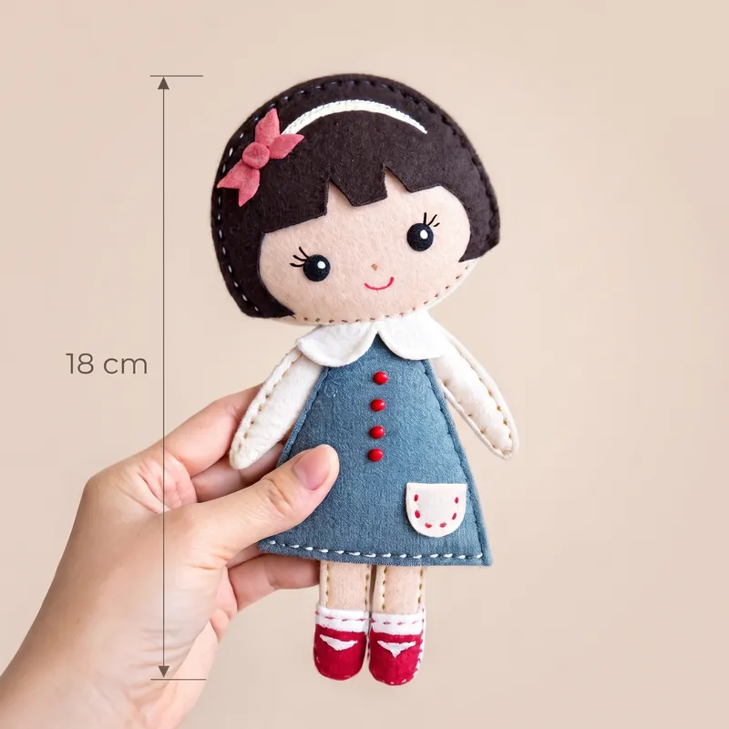 Finished simple felt doll with a dark bob and bow in a blue dress with red buttons